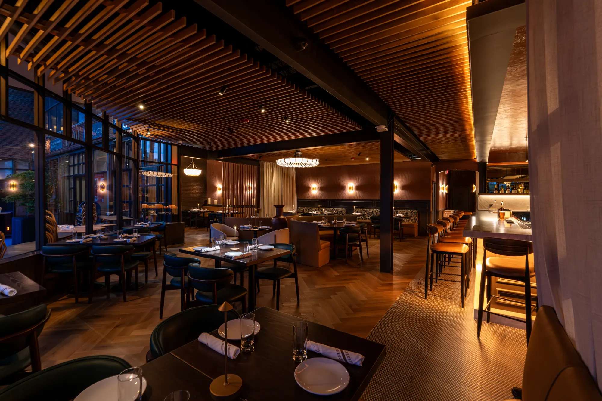 Restaurant dining room with a slatted wood ceiling in warm evening light